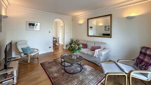 Ein Wohnzimmer mit einer Couch, Sesseln, einem Couchtisch und einem Essbereich im Hintergrund.