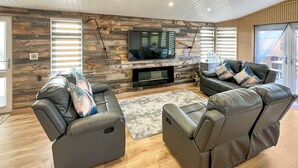 Una sala de estar moderna con chimenea, dos sofás de cuero, un televisor de pantalla plana y una pared de acento de madera.