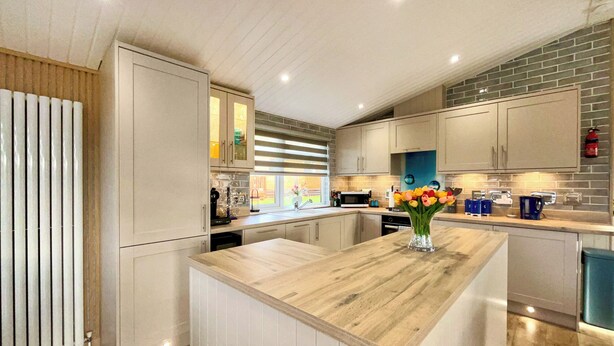 Una cocina moderna con una isla central, electrodomésticos integrados y vistas al exterior.