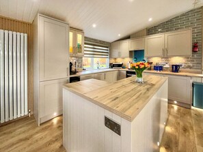 Een moderne keuken met een centraal kookeiland, inbouwapparatuur en uitzicht naar buiten.