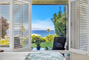 A bedroom with a view of the ocean, a chair, and a small table. - Kapalua Bay | Ocean View 3 BR, Sleeps 10 | Car Incl. w/ 6+ Nights | KBV ML-1975 by KBM (Lahaina)