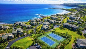 Zona residencial costera con casas, una cancha de tenis y vista al océano.