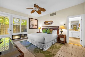 A bedroom with a bed, a ceiling fan, a nightstand with a lamp, a window with blinds, and a view of the bathroom. - Kapalua Bay | Ocean View 6 BR, Sleeps 20 | Car Incl. w/ 6+ Nights | KBV ML-1978 by KBM (Lahaina)