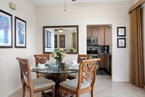 A dining area with a round glass table, wooden chairs, and a vase of flowers. - Kapalua Bay | Ocean View 6 BR, Sleeps 20 | Car Incl. w/ 6+ Nights | KBV ML-1978 by KBM (Lahaina)