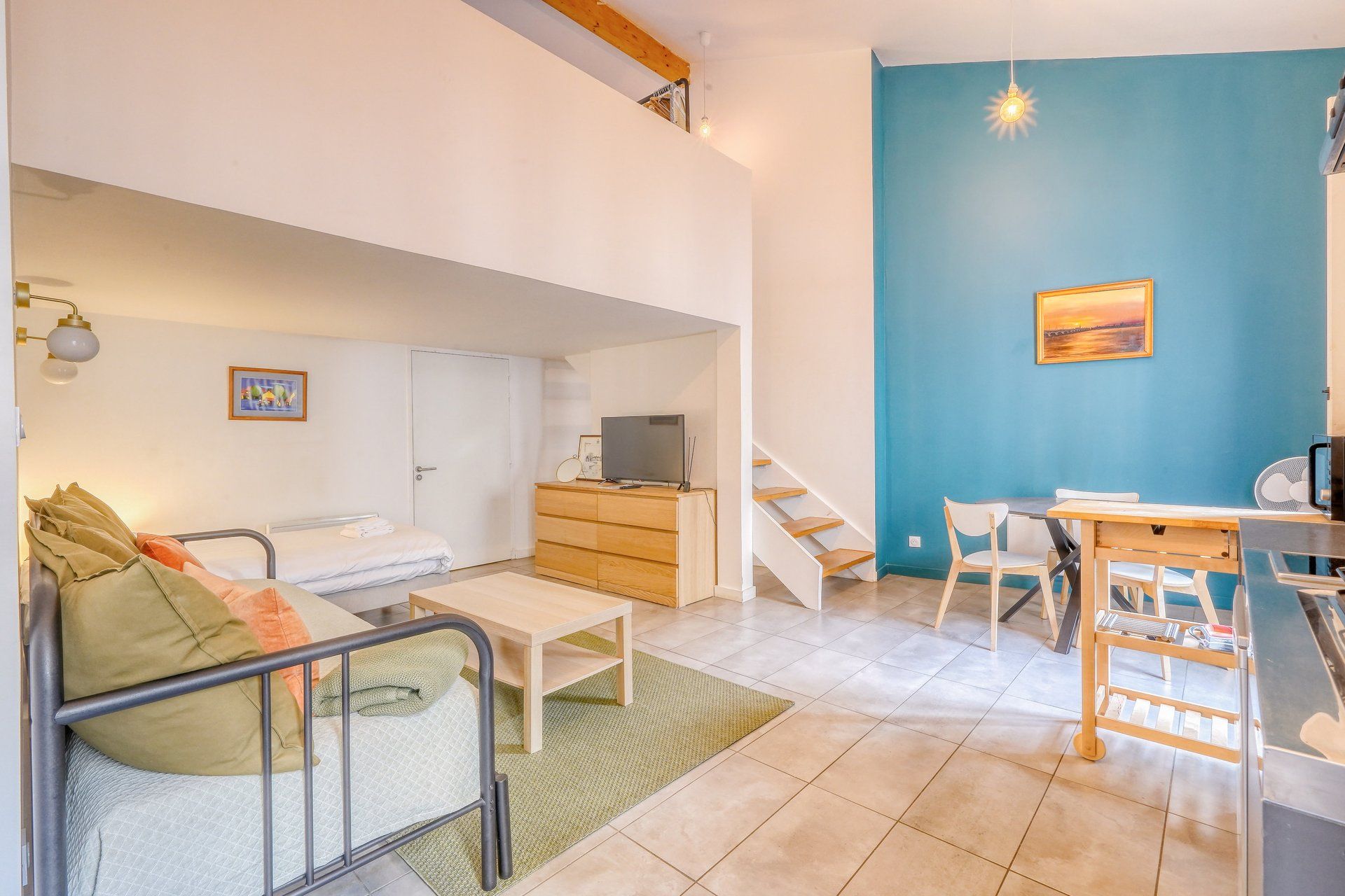 A modern apartment with a loft bedroom, a dining area, and a kitchen.