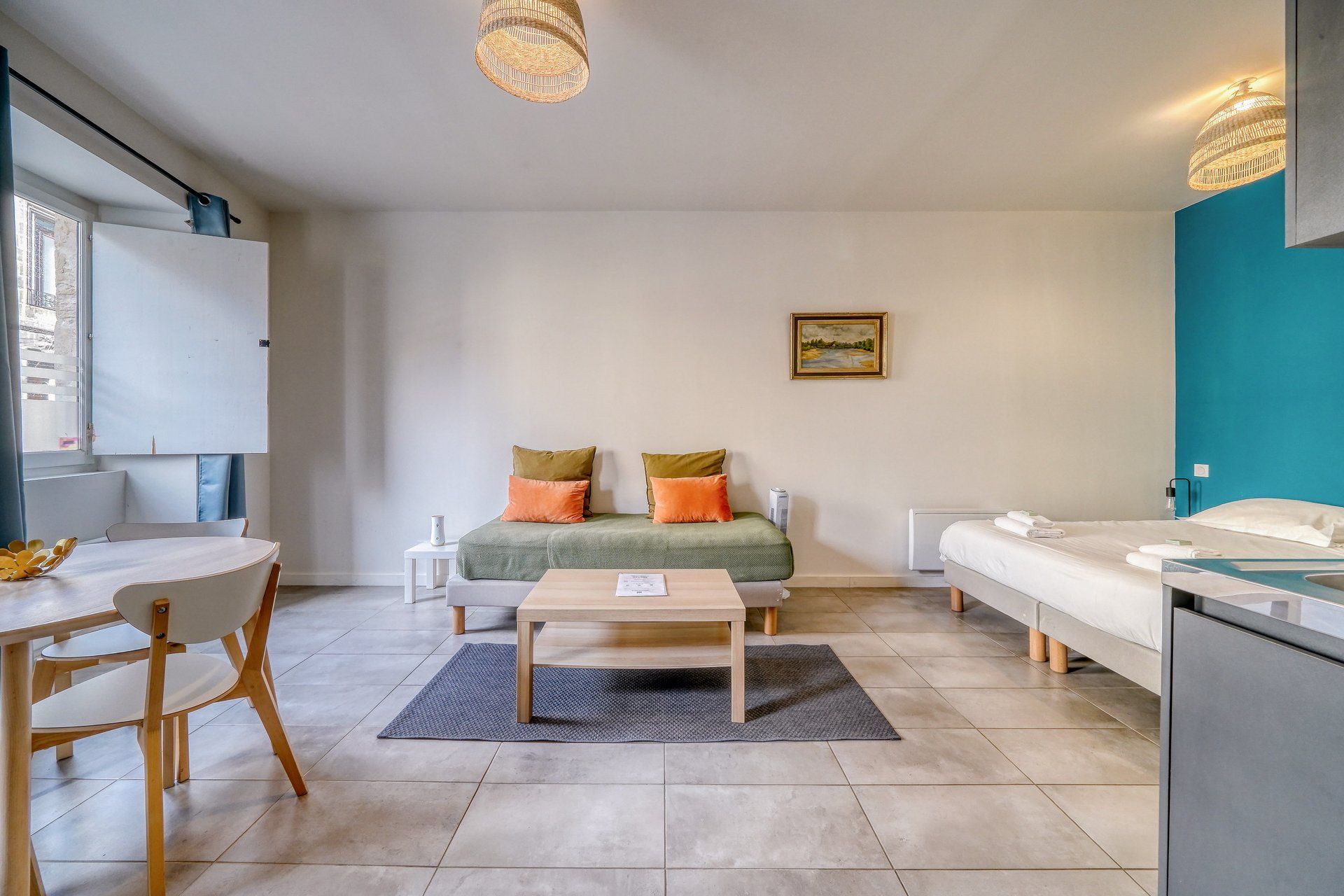 A modern, well-lit room with a sofa, a dining table, and a bed.