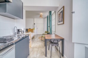 A compact kitchen with a sink, stove, and dining area with chairs. - Nice flat in Bordeaux-Saint-Jean (Bordeaux)
