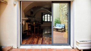 Una puerta corrediza de vidrio da acceso a un comedor con suelo de madera y un banco.