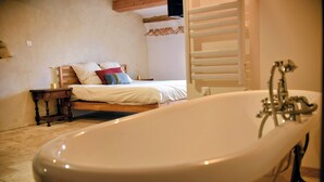Un dormitorio con una bañera grande, una cama de madera y una mesita de noche.
