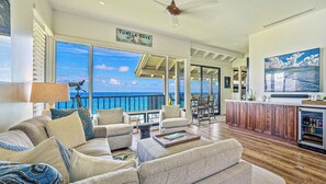 A spacious living area with a view of the ocean, a balcony with a railing, and a kitchen area with wooden cabinets. - Kapalua Bay | Ocean View 2 BR, Sleeps 6 | Car Incl. w/ 6+ Nights | KBV ML-1984 by KBM (Lahaina)
