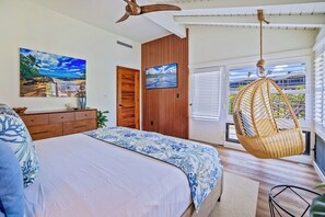 A bedroom with a bed, a dresser, a hanging chair, and a view of the outside. - Kapalua Bay | Ocean View 2 BR, Sleeps 6 | Car Incl. w/ 6+ Nights | KBV ML-1984 by KBM (Lahaina)