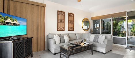 Een woonkamer met een bank, salontafel, televisie en decoratieve accessoires.