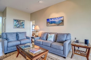 A living room with two grey sofas, a glass coffee table, a lamp, and a painting of a beach scene. - Kapalua Bay | Ocean View 3 BR, Sleeps 10 | Car Incl. w/ 6+ Nights | KBV ML-1969 by KBM (Lahaina)
