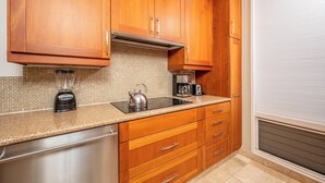 A kitchen with wooden cabinets, a stainless steel dishwasher, a kettle, and a coffee maker. - Kapalua Bay | Ocean View 3 BR, Sleeps 10 | Car Incl. w/ 6+ Nights | KBV ML-1969 by KBM (Lahaina)