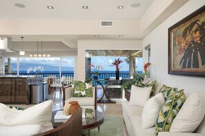 A modern living room with a view of the ocean, a dining area with a glass table, and a kitchen with stainless steel appliances. - Kapalua Bay | Ocean View 3 BR, Sleeps 8 | Car Incl. w/ 6+ Nights | KBV ML-1993 by KBM (Lahaina)