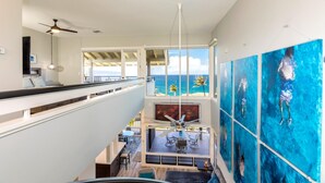 A spacious interior with a high ceiling, a dining area with a view of the ocean, and artwork on the walls. - Kapalua Bay | Ocean View 3 BR, Sleeps 10 | Car Incl. w/ 6+ Nights | KBV ML-2002 by KBM (Lahaina)