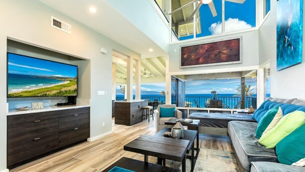 A spacious living area with a large flat-screen TV, a kitchen island, and a balcony with a view of the ocean. - Kapalua Bay | Ocean View 3 BR, Sleeps 10 | Car Incl. w/ 6+ Nights | KBV ML-2002 by KBM (Lahaina)