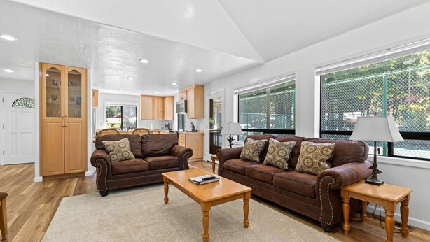 A spacious living room with two brown leather sofas, a wooden coffee table, and a beige rug. - Jed Smith Cabin with Tennis/Pickle ball courts and HOT TUB! (Crescent City)