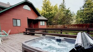 A hot tub on a wooden deck with a red building in the background. - Jed Smith Cabin with Tennis/Pickle ball courts and HOT TUB! (Crescent City)