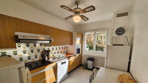 Una cucina compatta con mobili in legno, forno a incasso, microonde e una finestra vista alberi.