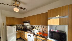 Una cucina con pensili in legno, un frigorifero bianco, un forno a microonde e una ventola a soffitto.