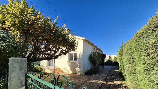 Una casa con vialetto lastricato e recinzione in metallo verde.