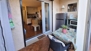 A small, enclosed balcony with a sliding glass door leading to a kitchen area. - Ground-floor studio, air conditioning, close to the sea, parking (ST MANDRIER SUR MER)