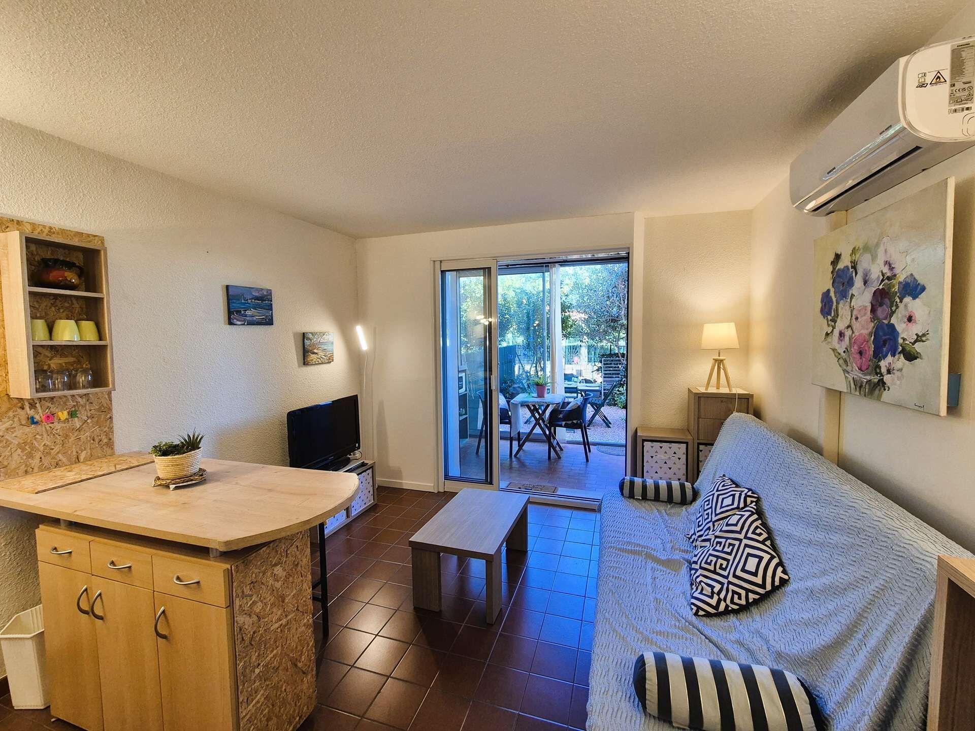 A compact living space with a kitchenette, a sofa, a TV, and a dining area with a table and chairs.