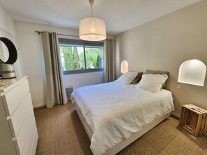 A bedroom with a bed, a dresser, a mirror, a window with curtains, and a wall-mounted light fixture. - 2-bedroom apartment, sea view, A/C, WiFi, pool (ST MANDRIER SUR MER)