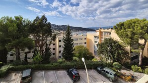 Ein Wohngebiet mit Mehrfamilienhäusern, einem Parkplatz und Blick auf eine ferne Stadt und Berge.