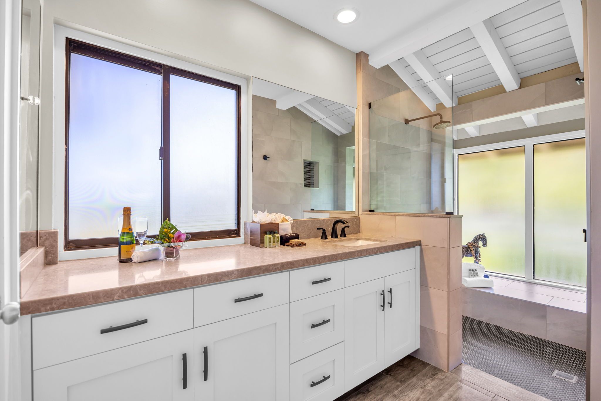 Une salle de bain moderne dotée d’un grand miroir, d’une zone de douche et d’un meuble-lavabo avec un plan de travail.
