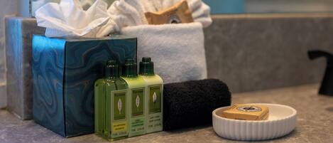 A bathroom counter with a box of toiletries, three bottles of shampoo, a black towel, and a soap dish.