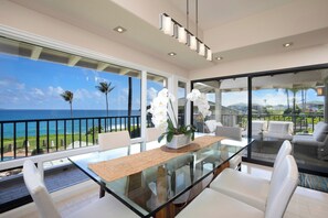Ein stilvoller Essbereich mit einem Glastisch, weißen Stühlen und Blick auf das Meer.