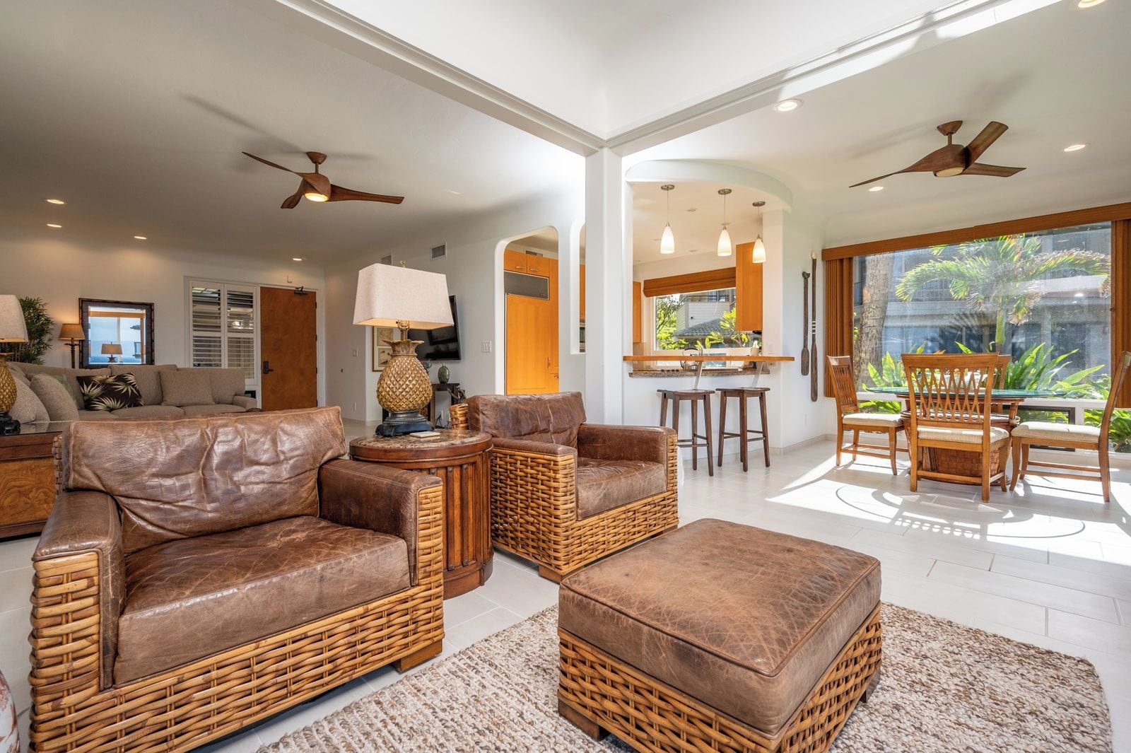 A spacious living area with leather sofas, wicker furniture, and a bar area with stools.
