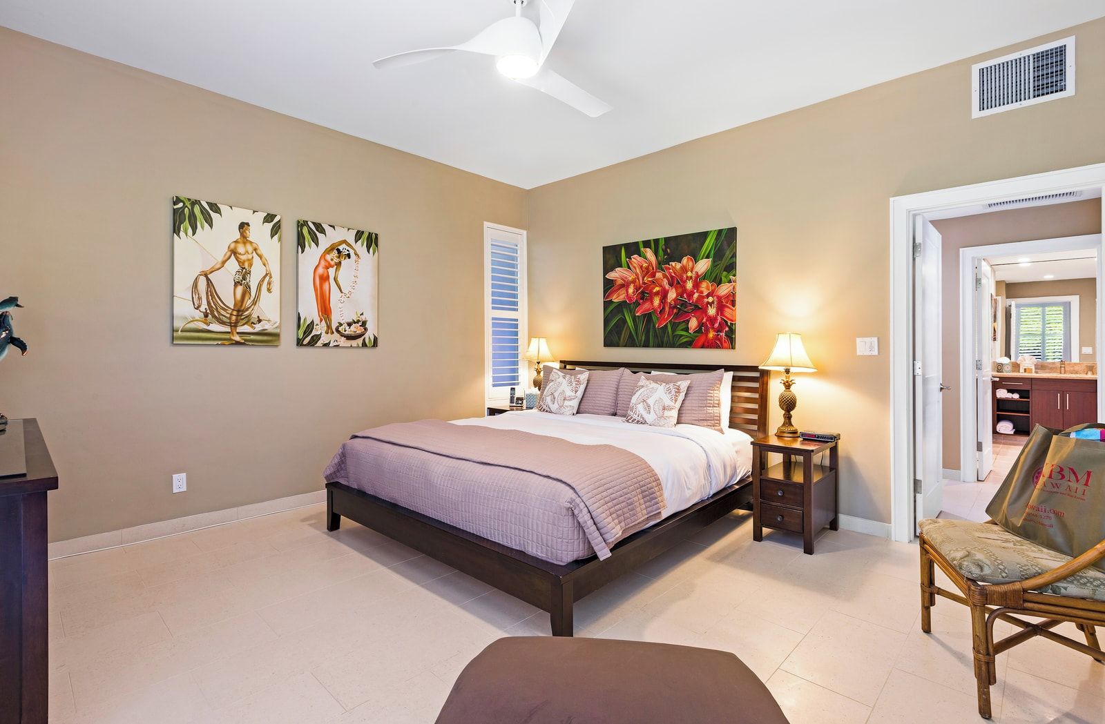 A bedroom with a bed, bedside tables, a chair, and artwork on the walls.