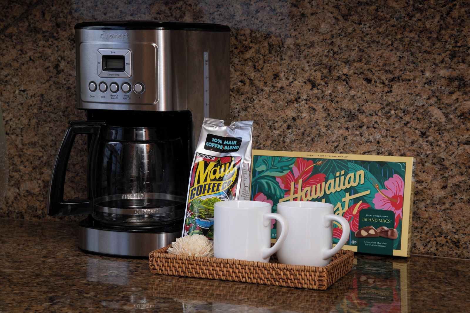 Eine Kaffeemaschine, ein Kaffeebeutel und eine Schachtel Hawaiian Island Macchiato auf einer Küchenarbeitsplatte.
