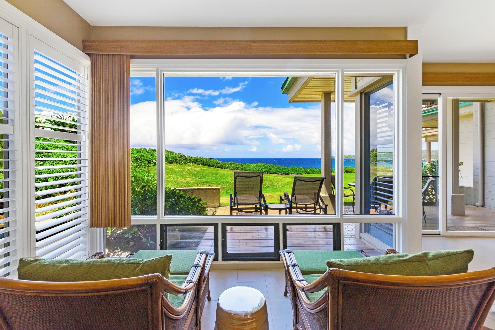 A room with a large sliding glass door leading to a balcony with a view of a green landscape and the ocean.