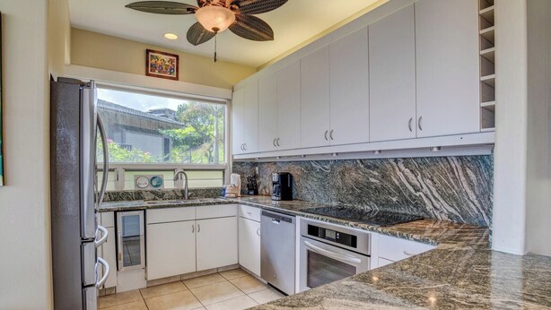 A modern kitchen with white cabinets, granite countertops, a built-in oven, and a ceiling fan. - Kapalua Bay | Ocean View 5 BR, Sleeps 16 | Car Incl. w/ 6+ Nights | KBV ML-2026 by KBM (Lahaina)