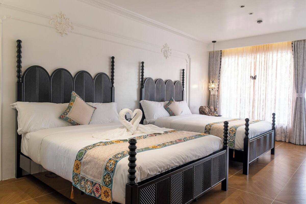 Une chambre d’hôtel avec deux lits, chacun doté d’une tête de lit noire et de draps blancs.