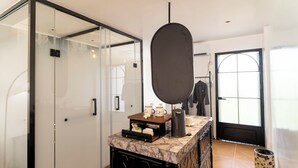 A modern bathroom with a glass shower enclosure, a marble countertop, and a large mirror. - Madeline Paradise Resort (Panglao)