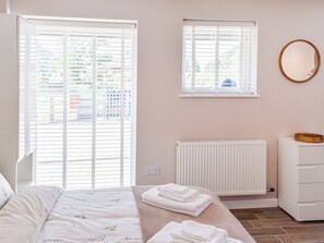 A bedroom with a bed, a window, a radiator, and a dresser.