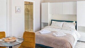 Et hotelværelse med seng, stol, bord og bruser.