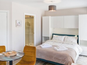 A hotel room with a bed, a chair, a table, and a shower. - 1 bedroom accommodation in Lydney, Forest of dean (Lydney, Forest of dean)