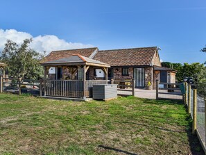 A two-story building with a tiled roof, a covered patio area, and a fenced yard.