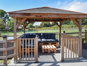 A wooden gazebo with a bench and a table, surrounded by a fence. - 1 bedroom accommodation in Lydney, Forest of dean (Lydney, Forest of dean)