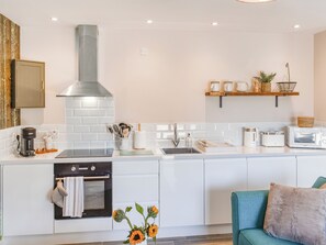 A modern kitchen with a built-in oven, a stainless steel range hood, a sink, and a microwave.