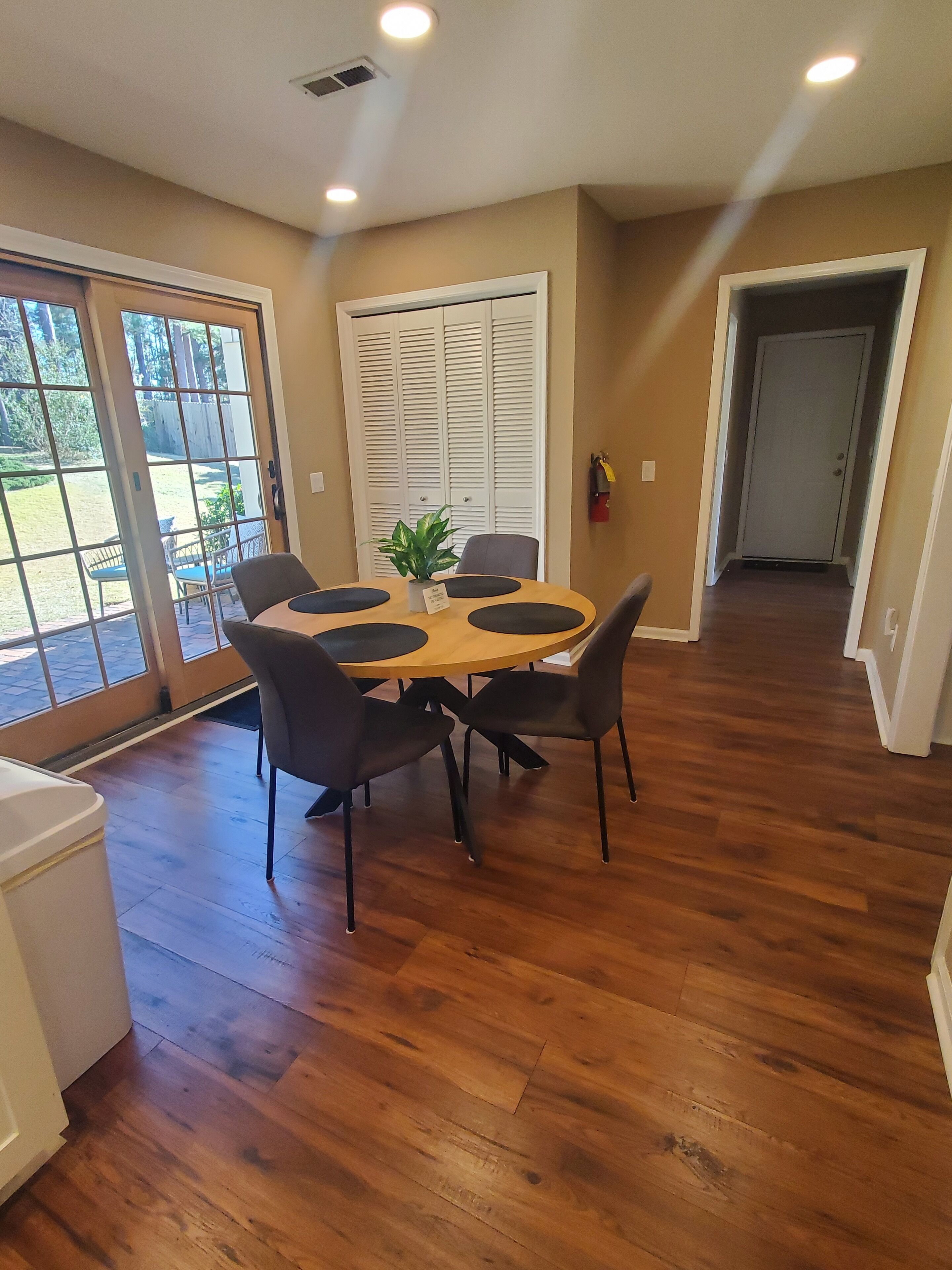 A dining area with a round table, four chairs, and a potted plant.