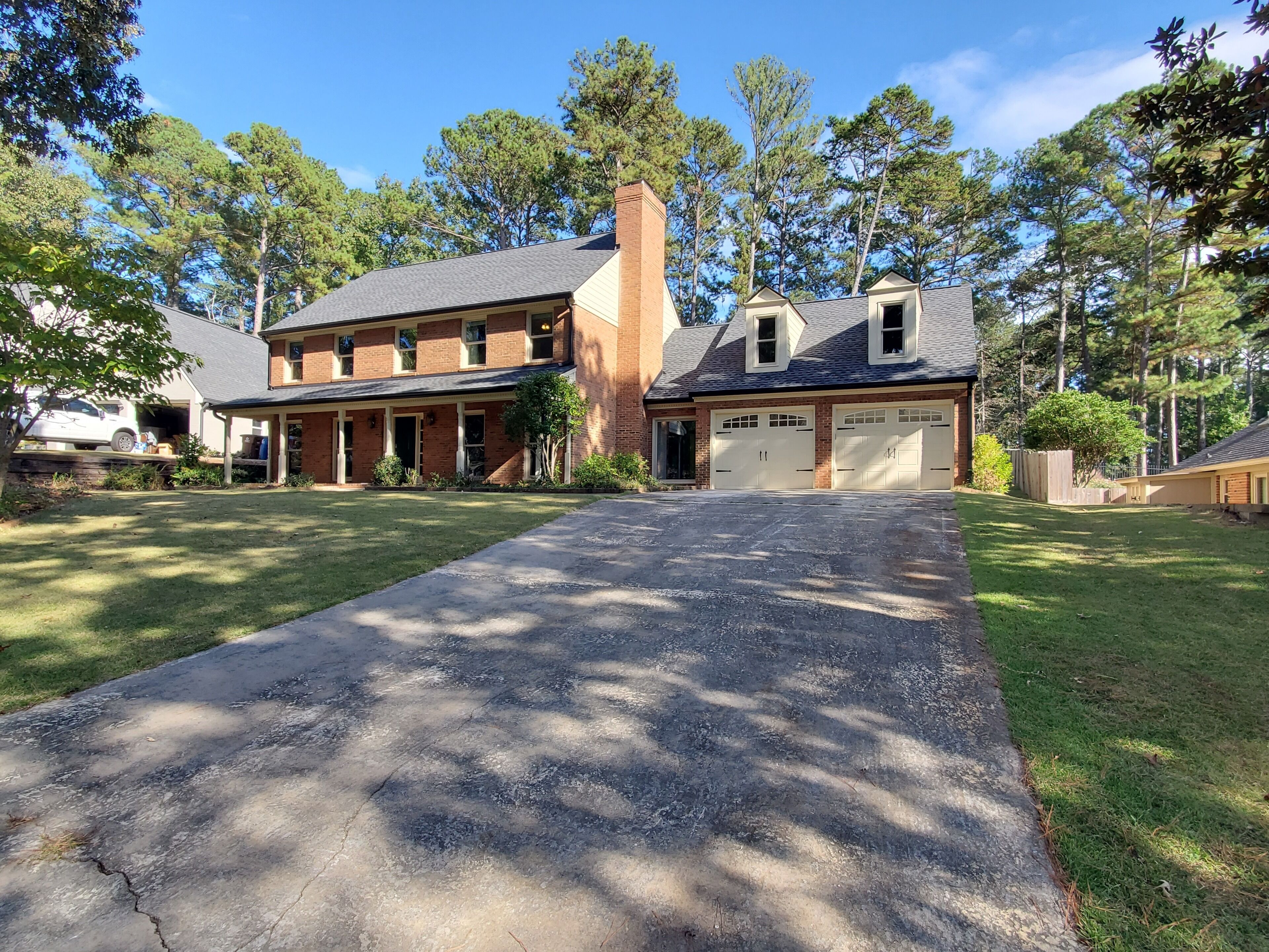 A two-story house with a front driveway, garage, and a large lawn.