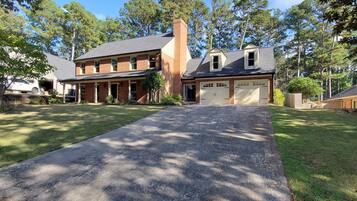 A two-story house with a front driveway, garage, and a large lawn.