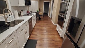 Una cocina moderna con armarios blancos, electrodomésticos de acero inoxidable y suelo de madera.